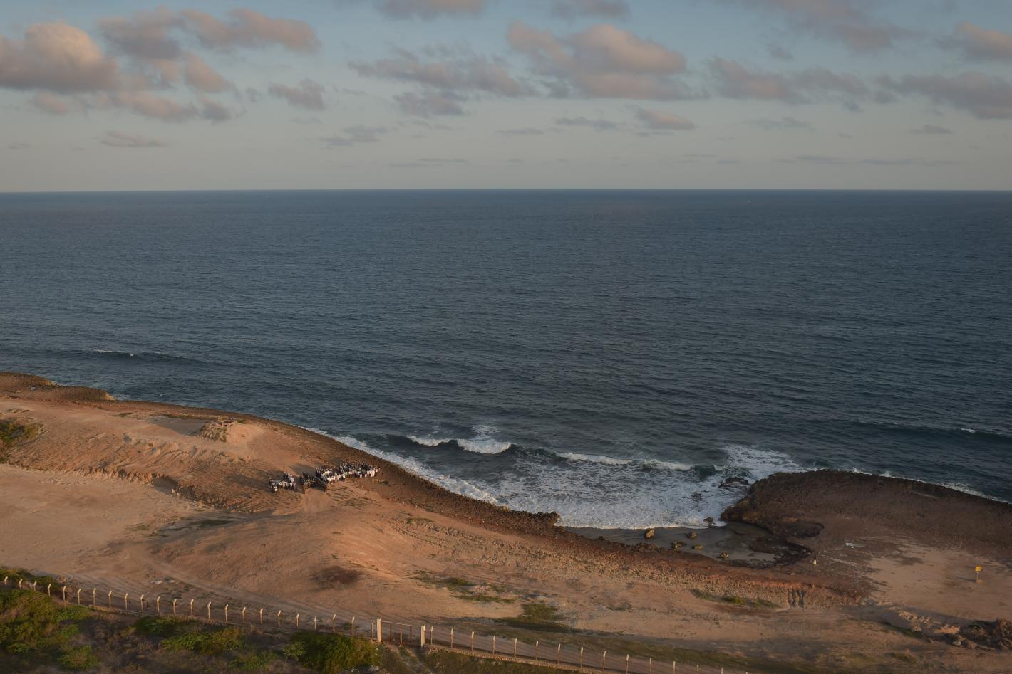 A photo of a beach in Somalia where some cars and people can be seen