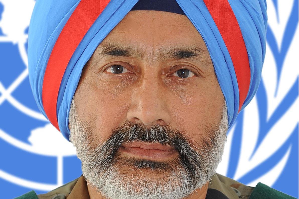 A headshot of a man in military uniform in front of a UN logo